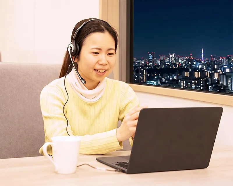 夜景の見える部屋でノートパソコンでレッスンを受ける女性